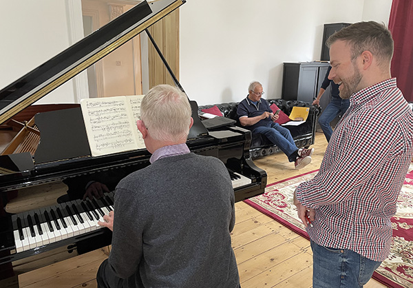 Image of David Quigley with a student on a piano course
